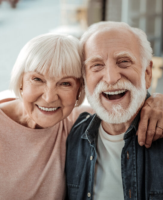 A cheerful elderly couple smiles closely, representing renewed health after extractions at Mountainview Periodontics